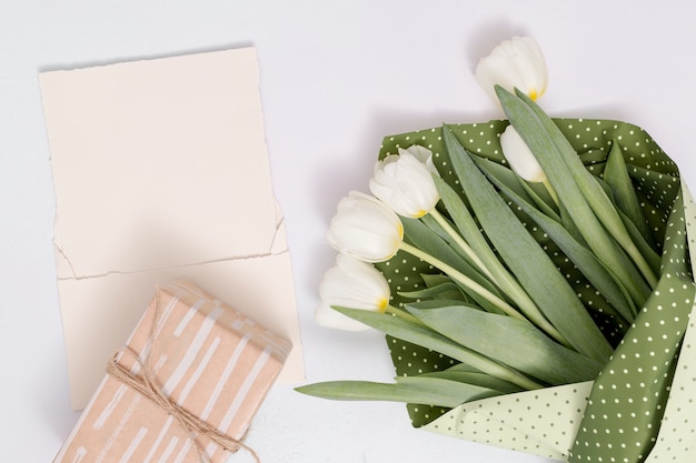 Erhöhte Ansicht der weißen Tulpe blüht Blumenstrauß; Geschenkbox mit leerem Papier auf weißem Hintergrund