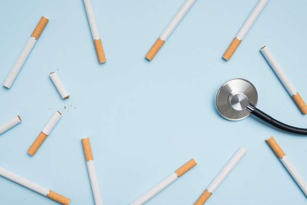 Kostenloses Foto erhöhte ansicht der zigarette und des stethoskops auf blauem hintergrund