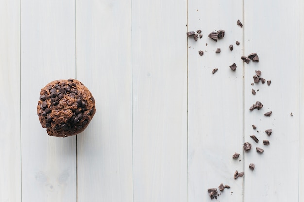 Erhöhte Ansicht des choco Chipkleinen kuchens und der zerstreuten Schokolade auf hölzernem Hintergrund