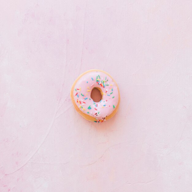 Erhöhte Ansicht des Donuts mit besprüht auf rosa Hintergrund