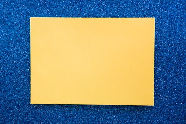 Erhöhte Ansicht des gelben Papppapiers auf blauem Hintergrund