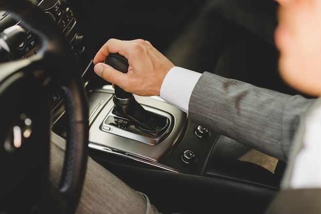 Erhöhte Ansicht des Geschäftsmannes fahrenden Bewegungsverschiebungsgang des Autos bewegend