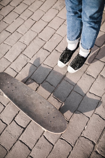 Kostenloses Foto erhöhte ansicht des skateboarders bein und skateboard auf bürgersteig