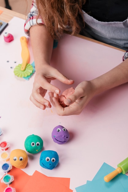 Erhöhte Ansicht einer Hand, die farbigen Lehm für die Herstellung von Handwerkskunst hält