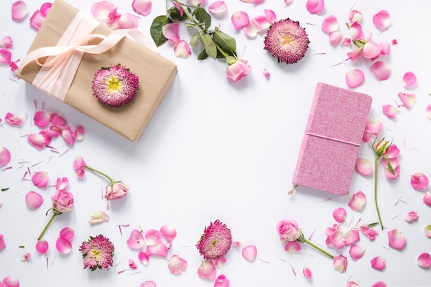 Erhöhte Ansicht von Blumen; Geschenkbox und Tagebuch auf weißer Oberfläche