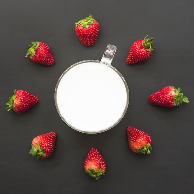 Erhöhte Ansicht von Erdbeeren und von Milch auf schwarzem Hintergrund