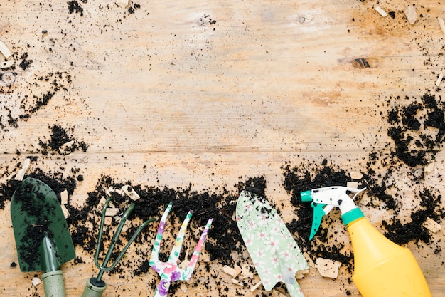 Kostenloses Foto erhöhte ansicht von gartenarbeitausrüstungen vereinbarte auf boden gegen holztisch