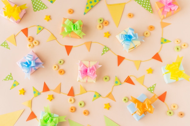 Erhöhte Ansicht von Geburtstagsgeschenken; Bunting und Froot Loops Bonbons auf farbigem Hintergrund