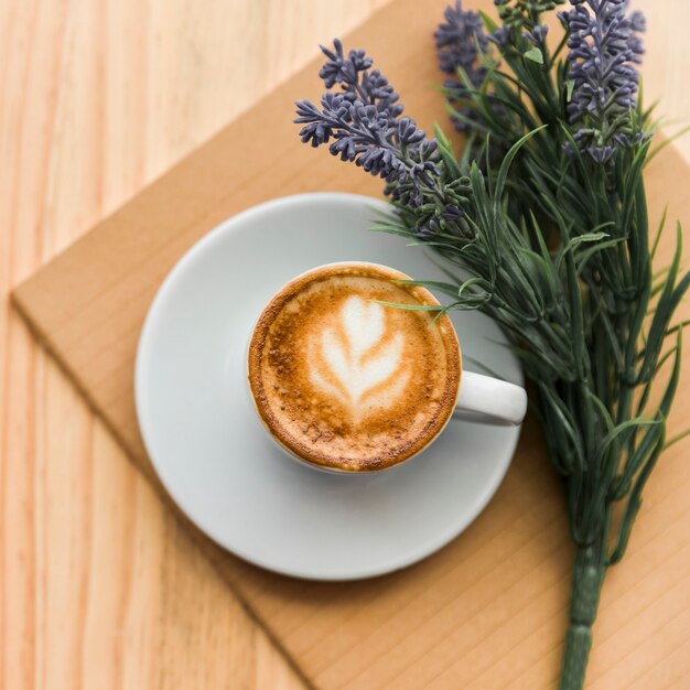 Erhöhte Ansicht von Kaffee Latte, von Notizbuch und von Lavendel blühen