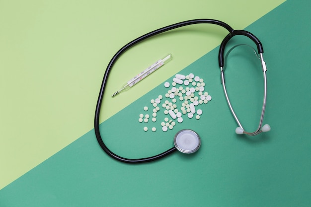 Erhöhte Ansicht von Medikamenten; Thermometer und Stethoskop auf zwei farbigen Hintergrund