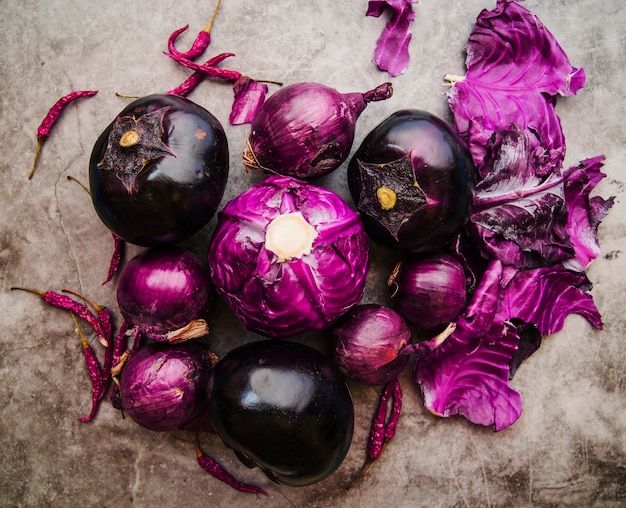 Erhöhte Ansicht von Purpurkohl; Aubergine; Zwiebel und rote Chilischoten am Boden