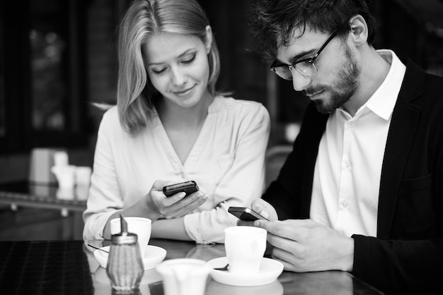 Erholsamer Paar mit Smartphone im Coffee-Shop verbunden