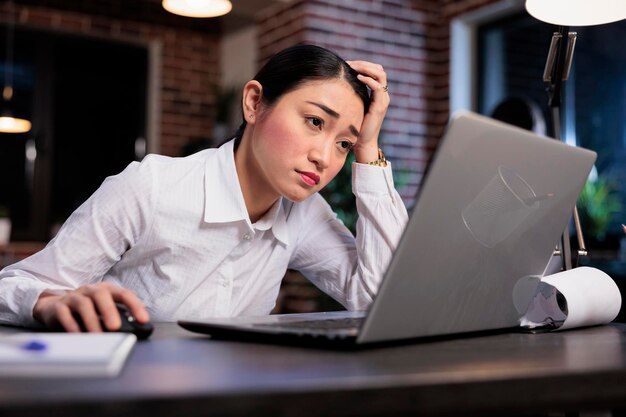 Ermüdeter Mitarbeiter einer Marketingfirma mit schmerzhaften Kopfschmerzen, die müde im Büroarbeitsplatz sitzen. Erschöpfter Finanzberater mit Burnout-Syndrom, gestresst wegen Projekttermin.