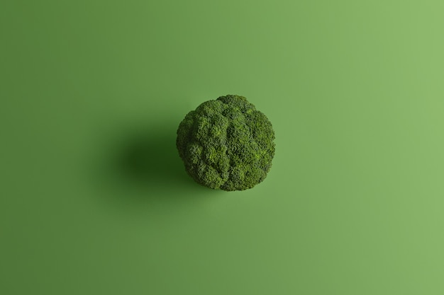 Ernährungsgesunder Brokkoli, der von oben auf grünem Hintergrund fotografiert wird. Leckeres Gemüse kann roh und gekocht gegessen werden. Quelle von Vitaminen. Koch- und Essenskonzept. Nährstoffreiche Kohlsorte