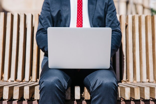 Erneuerngeschäftsmann, der Laptop auf Bank durchstöbert