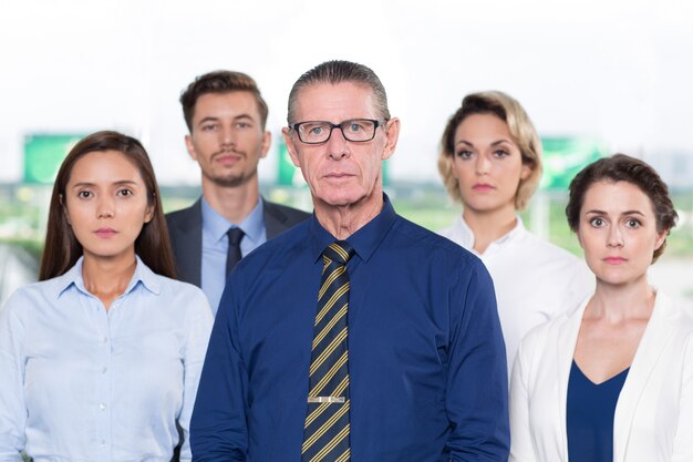 Ernste ältere Business Leader Standing mit dem Team