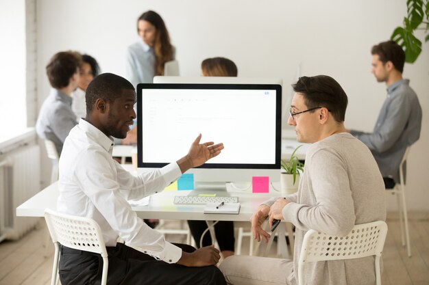 Ernste gemischtrassige Kollegen, die zusammen ein Brainstormingprojekt im Büro haben