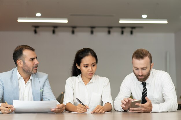 Ernste Geschäftsleute, die mit Dokumenten am Schreibtisch arbeiten