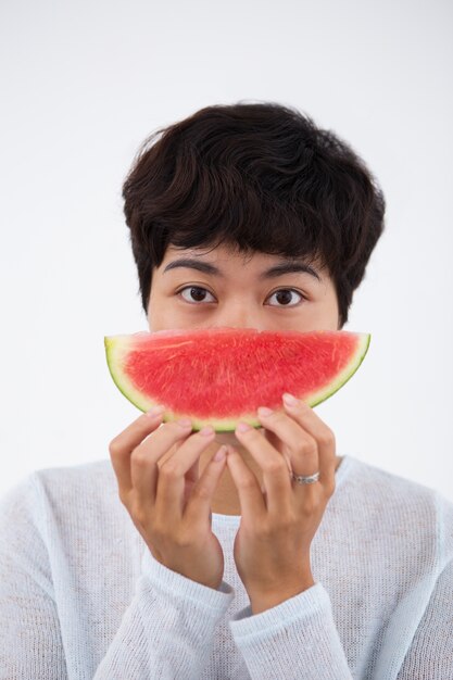 Ernste junge asiatische Frau hält Wassermelone