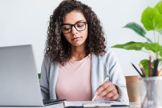 Ernste junge Frau, die im Büro arbeitet