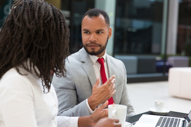 Kostenloses Foto ernste junge kollegen, die arbeitsfragen besprechen