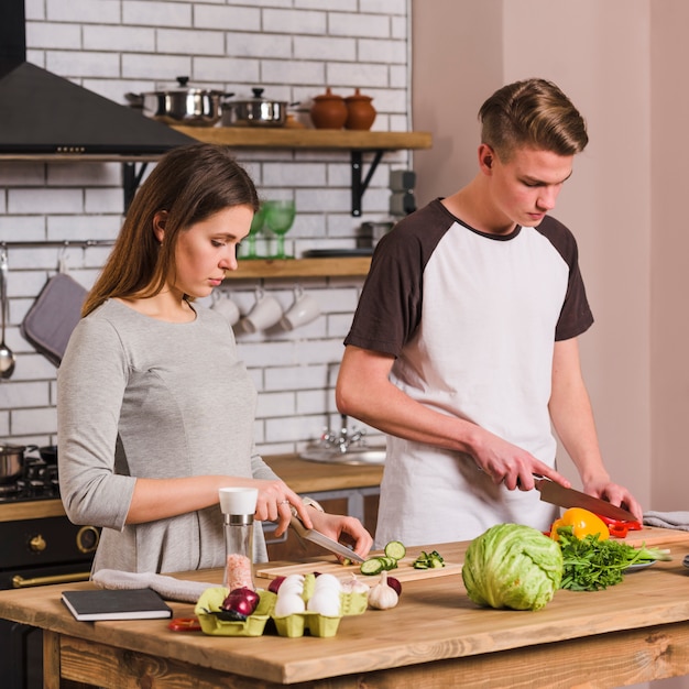 Ernste junge paare, die lebensmittel kochen