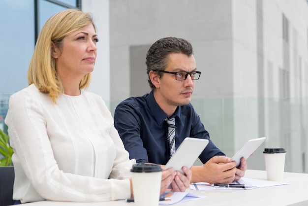 Ernste männliche und weibliche Kollegen, die Café im im Freien arbeiten.