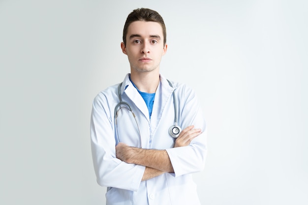 Ernster attraktiver junger männlicher Doktor mit Stethoskop