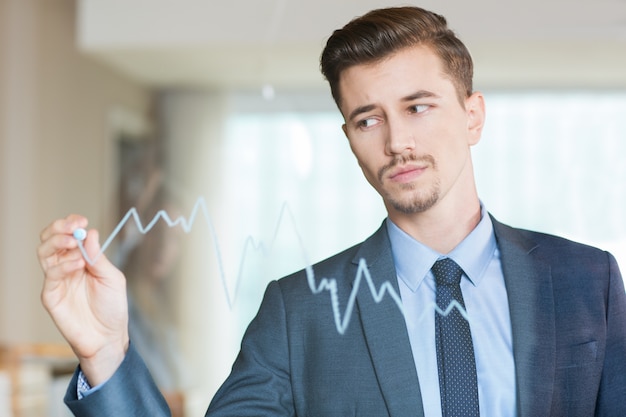 Ernster Geschäftsmann Zeichnung Diagramm auf Glas-Board