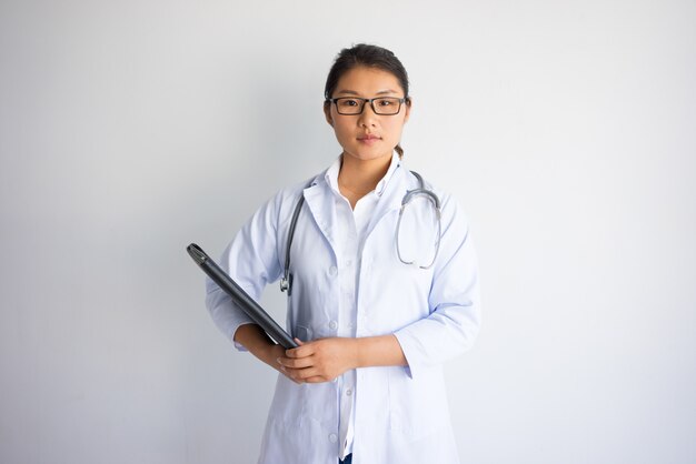 Ernster junger asiatischer weiblicher Doktor, der Ordner hält. Doktor Beruf Konzept.