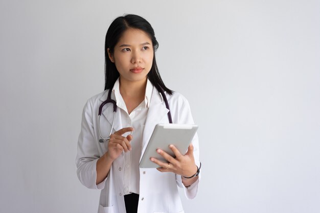 Ernster junger weiblicher Doktor, der Tablet-Computer verwendet