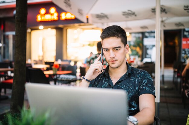 Ernster Mann, der auf Mobiltelefon in cafÃ? Spricht