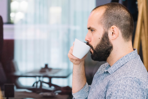 Kostenloses Foto ernster mann, der kaffee versucht