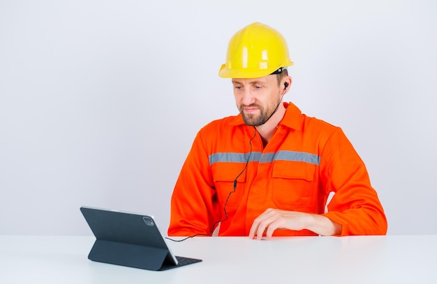 Ernsthaft sitzt der Ingenieur vor dem Tablet auf weißem Hintergrund