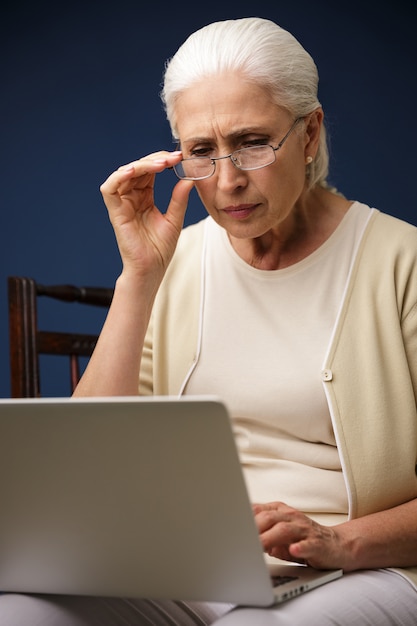 Ernsthafte alte Frau mit Laptop-Computer. Zur Seite schauen.