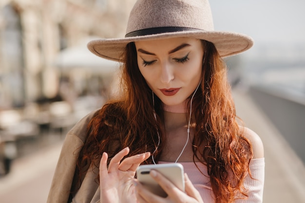 Ernsthafte Frau mit langen dunklen Haaren, die Telefonbildschirm betrachten