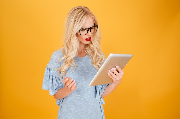 Ernsthafte junge blonde Frau mit Tablet-Computer.