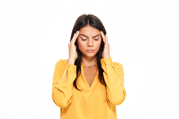 Ernsthafte junge Dame mit Kopfschmerzen im gelben Hemd