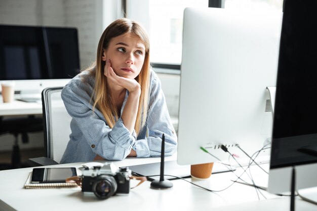 Ernsthafte junge Frau arbeiten im Büro unter Verwendung des Computers