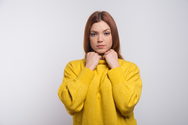 Ernsthafte junge Frau im gelben Pullover