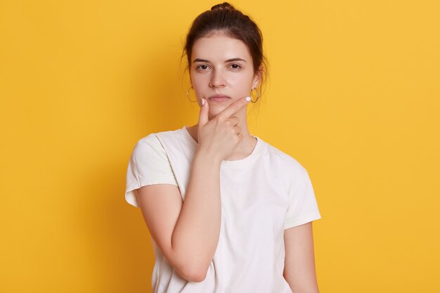 Ernsthafte junge junge Frau, die weißes T-Shirt trägt