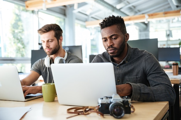 Ernsthafte junge Kollegen sitzen im Büro Coworking