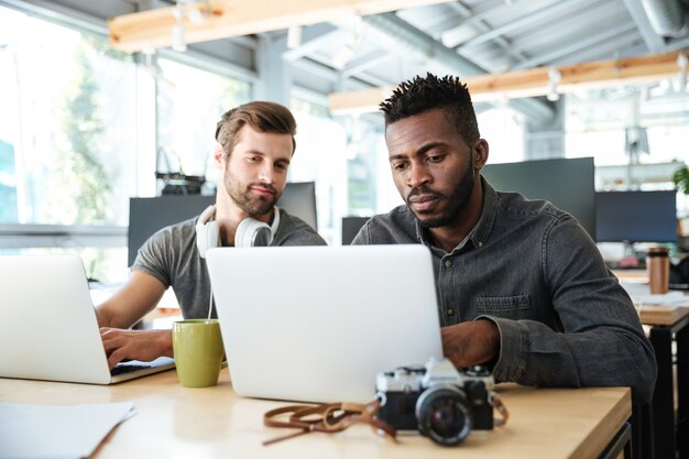 Ernsthafte junge Kollegen sitzen im Büro Coworking