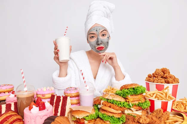 Ernsthafte selbstbewusste Frau schaut ernst in die Kamera, umgeben von Fast Food