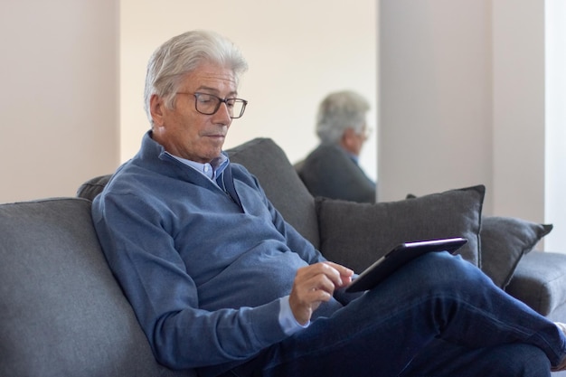 Ernsthafter älterer Geschäftsmann, der mit Tablet arbeitet