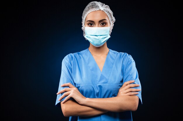 Ernsthafter Arzt in der medizinischen Maske und in der Kappe suchen