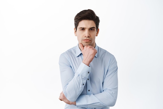 Ernsthafter Geschäftsmann Brainstorming Blick in die Kamera und denke, dass er nachdenklich steht und wichtige Entscheidungen bei der Büroarbeit auf weißem Hintergrund trifft