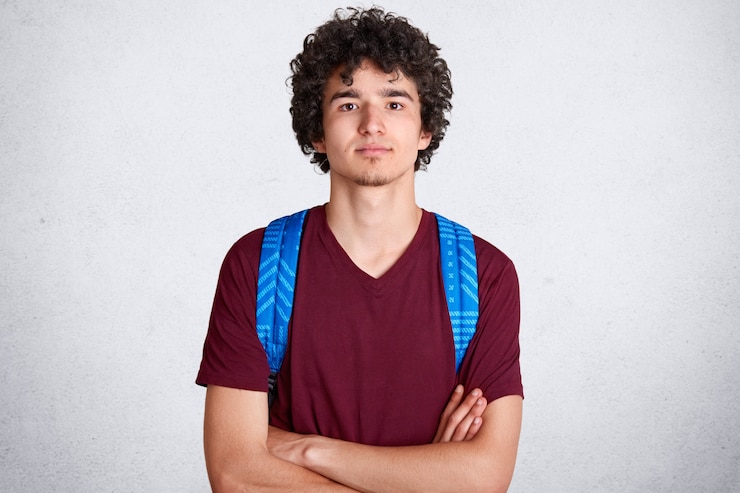 Kostenlose Foto ernsthafter nachdenklicher junger student, der direkt in die kamera schaut