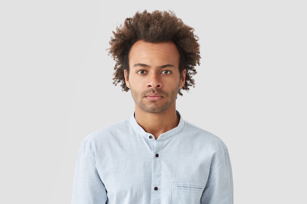 Ernsthafter, selbstbewusster Mann mit lockigem Haar, sieht konzentriert aus, trägt ein weißes Hemd und hört aufmerksam zu