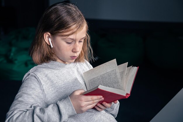 Ernsthaftes kleines Mädchen, das ein Buch liest, verschwommener Hintergrund